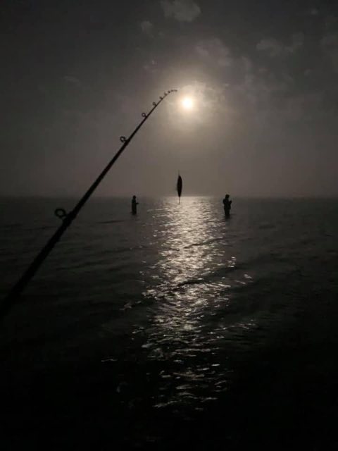Wading anglers under the moon