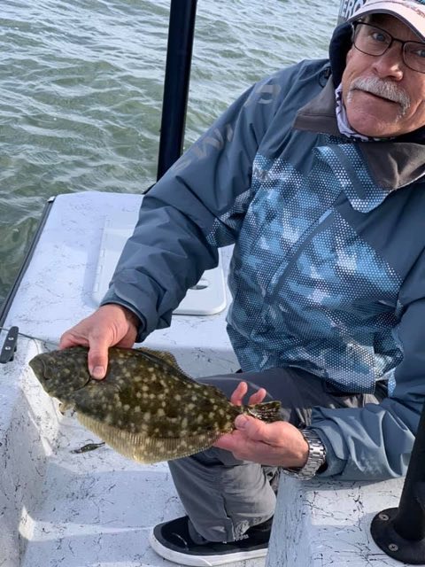 Angler holding a flounder on the boat