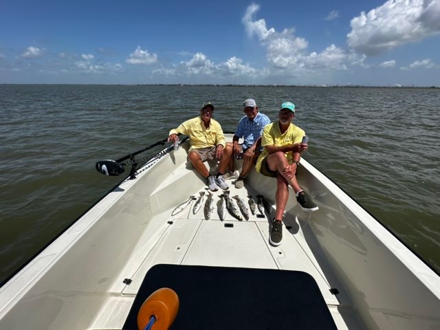 Three anglers on the bow with a row of speckled trout