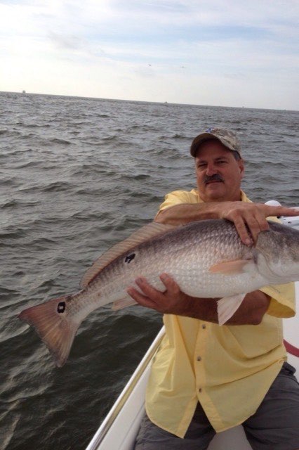Angler in a yellow shirt with a big redfish
