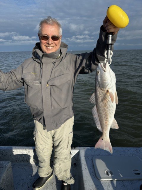 Angler holding up a redfish on the boat