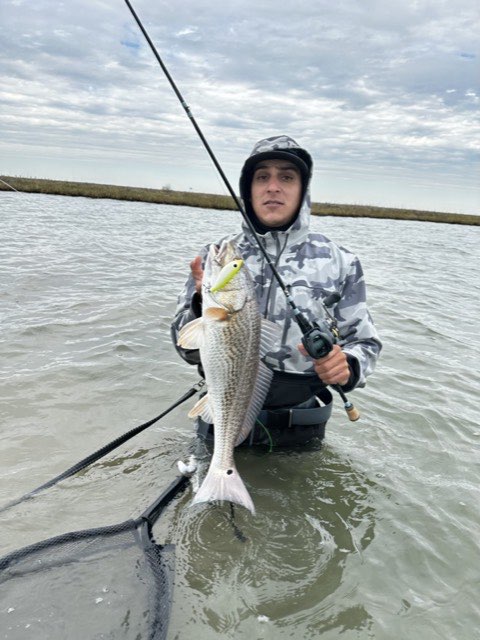 Wading angler with a redfish and a landing net