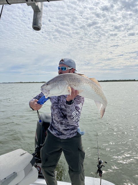 Angler holding a redfish on the boat