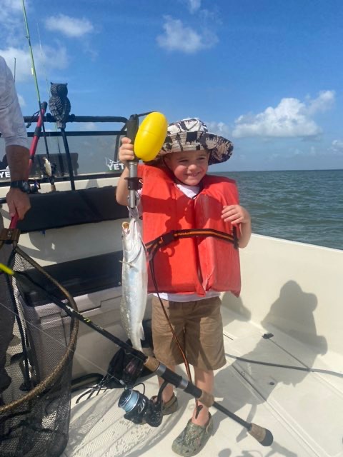 Young angler in a life jacket with a trout on the scale