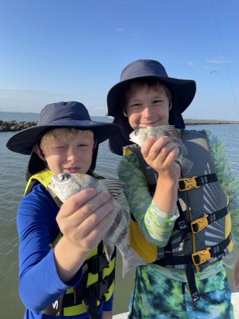 Two young anglers in life jackets with their catch