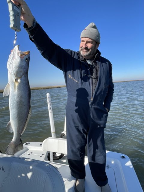 Angler in a beanie weighing a big speckled trout