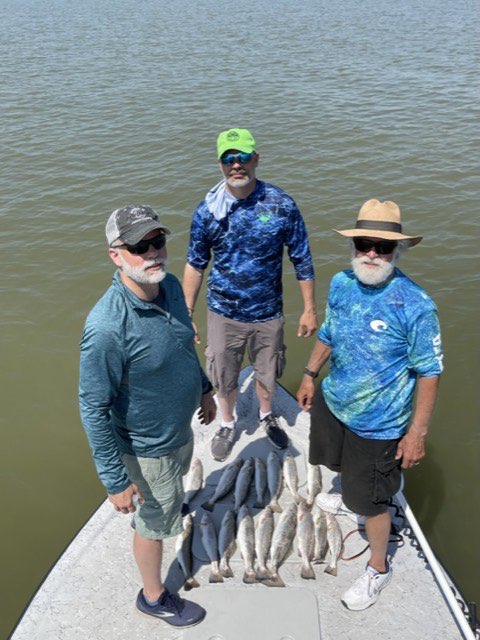Three anglers on the bow with a stringer of trout