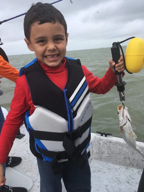 Smiling young angler with a trout on the scale
