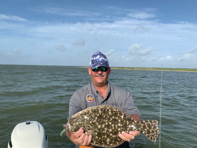 Angler holding a big flounder on the boat