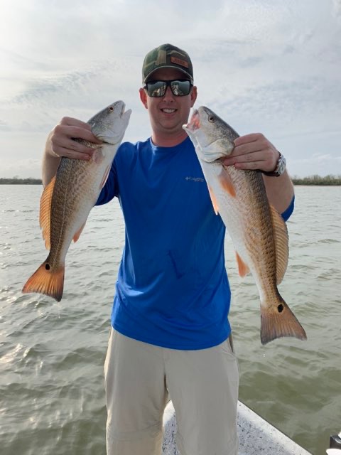 Angler holding up two redfish