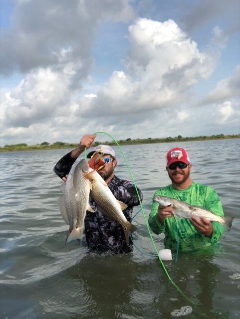 Two wading anglers holding up their fish