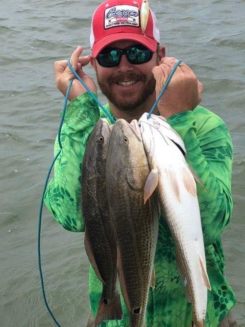 Angler in a red cap with a stringer of speckled trout