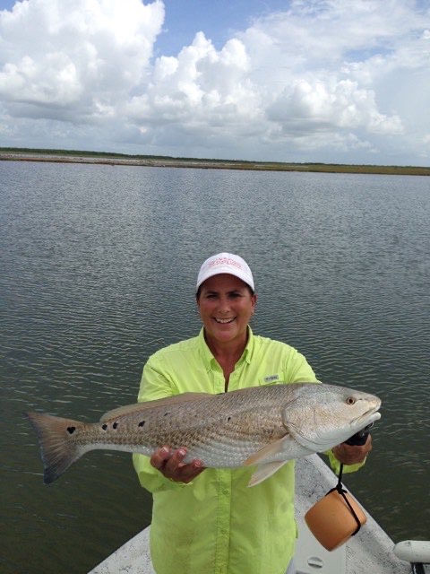 Angler in a bright green shirt with a redfish