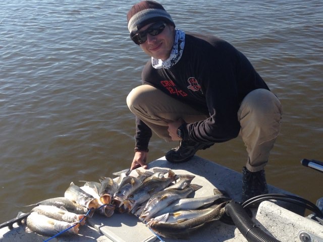 Angler crouched over a pile of trout on the deck