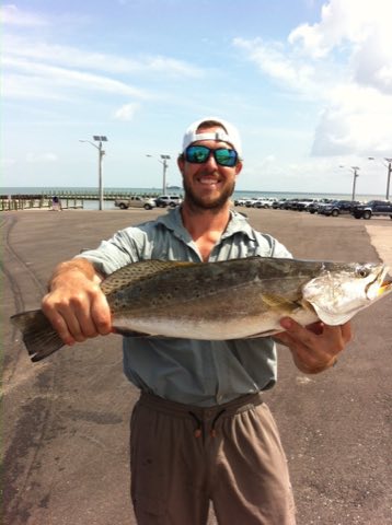 Angler holding a big speckled trout on the pier