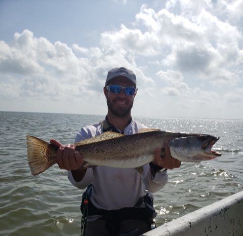Angler holding a big speckled trout across the bow