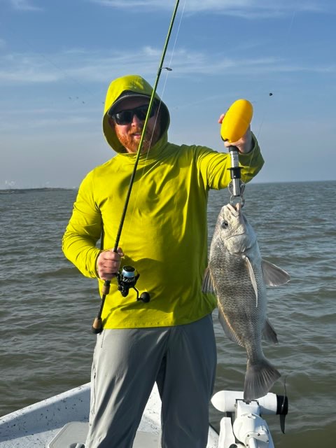 Angler in a yellow hoodie with a black drum
