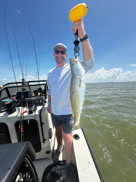 Angler holding up a speckled trout on the scale