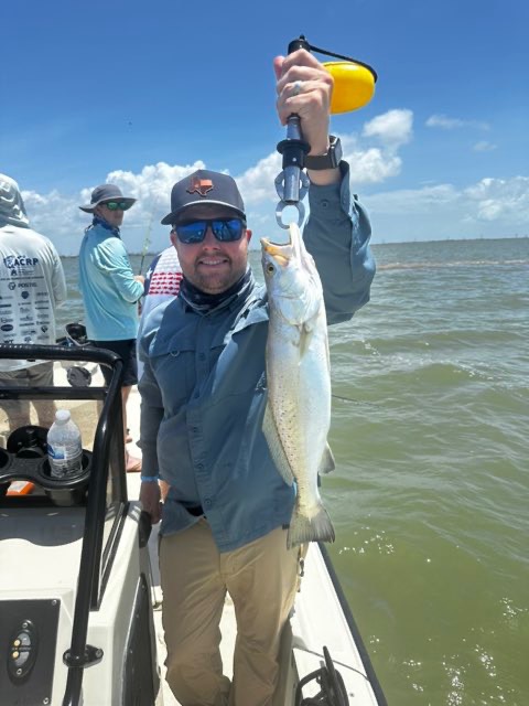 Angler with a speckled trout while the crew fishes behind