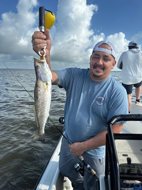 Smiling angler with a speckled trout on the scale