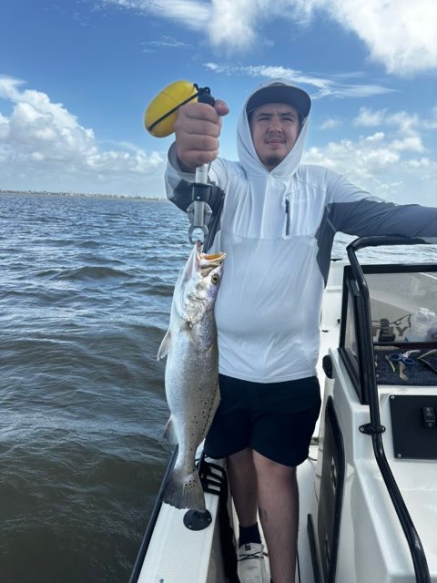Angler in a sun hoodie with a speckled trout