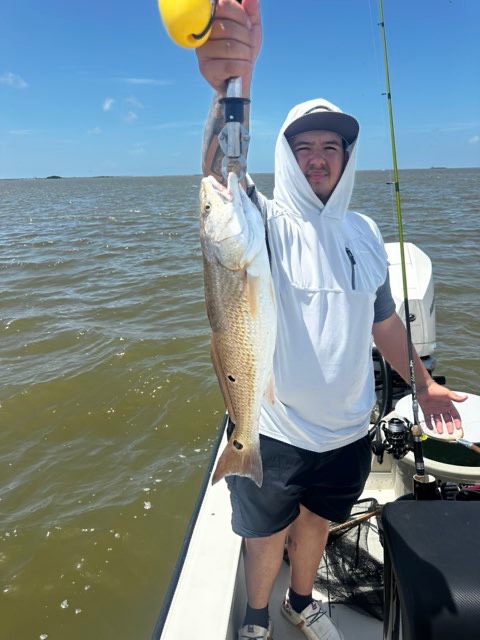 Angler in a white hoodie with a redfish