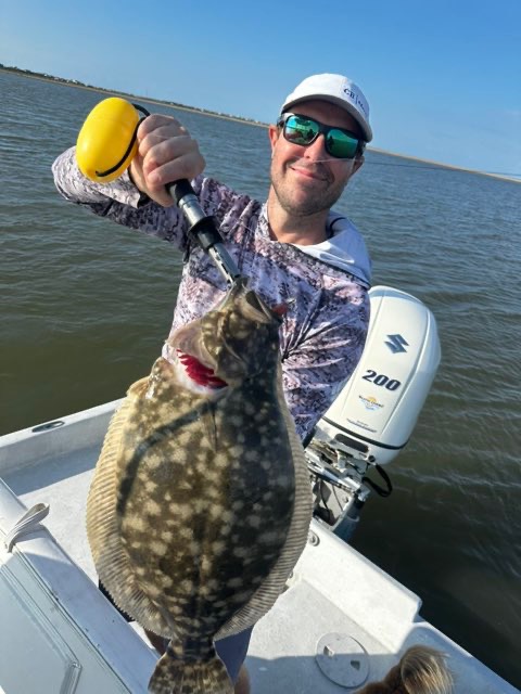 Angler holding up a big flounder on the boat