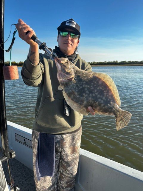 Angler holding up a flounder on the boat