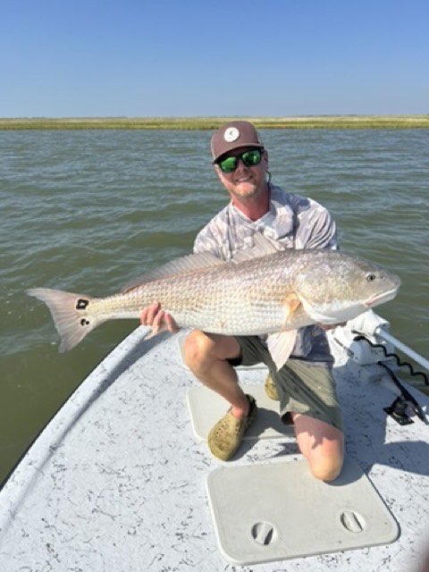 Angler kneeling on the bow with a redfish