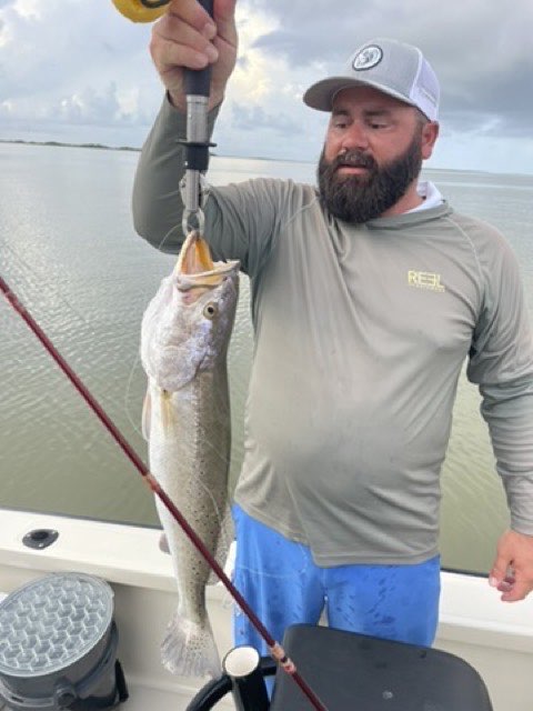 Angler holding up a speckled trout on the boat
