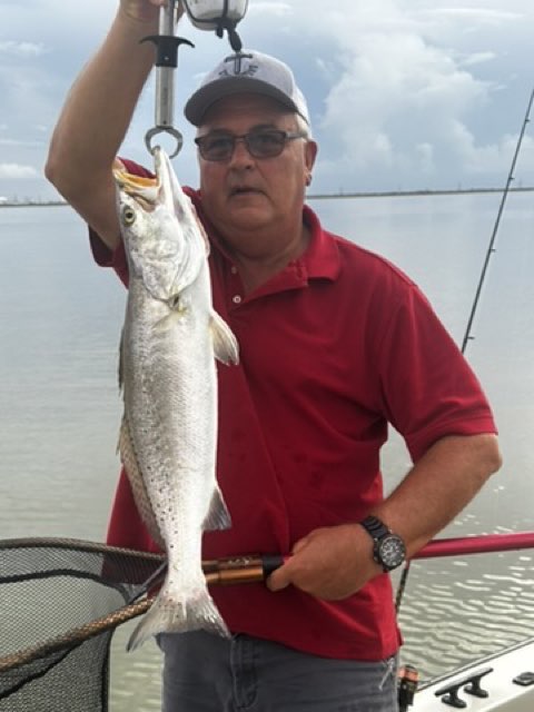 Angler in a red shirt with a speckled trout