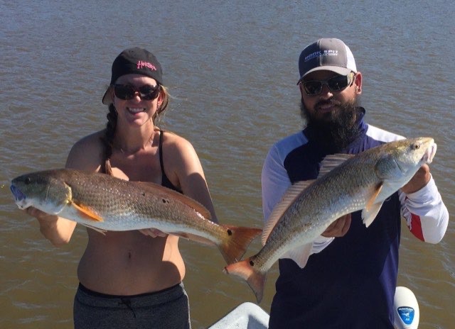 Two anglers holding redfish side by side
