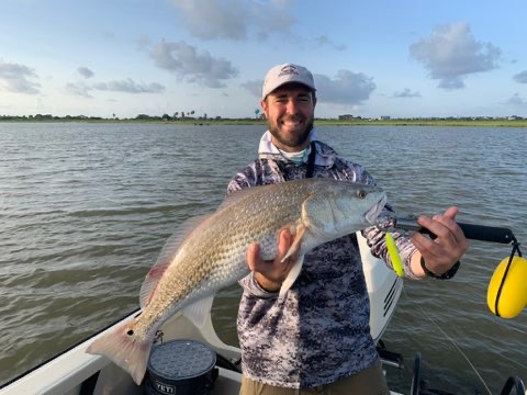 Angler on the boat with a big trout caught on topwater