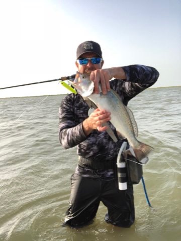 Wading angler with a trout caught on topwater