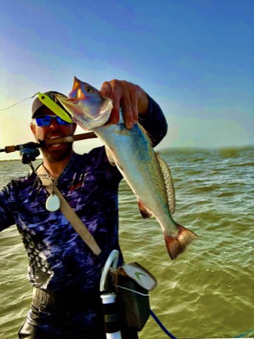 Angler holding up a trout caught on topwater