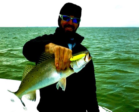 Angler with a speckled trout caught on topwater
