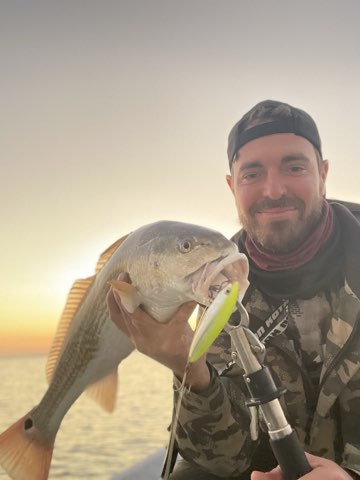 Angler with a big trout on topwater at sunrise